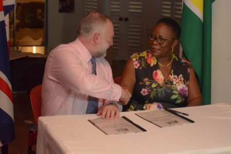 National Hydrographer of the UK Hydrographic Office, Rear Admiral Tim Lowe, and the Director General of the Maritime Administration Department, Claudette Rogers shake hands shortly after signing the data release statement.  (Department of Public Information photo)   
