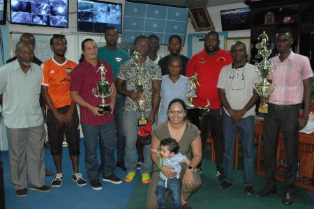 Prize winners pose with their hardware along with Brian Tiwarie’s daughter and grandson (stooping) at the Company’s Head Office on Monday.