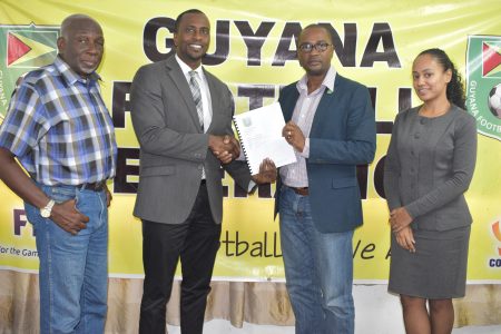 GFF President Wayne Forde (2nd right) presenting the Disciplinary Code to GFF Disciplinary Committee Chairman Roger Yearwood in the presence of two other committee members.