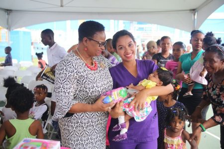  The Ministry of Social Protection continued its 2018 Christmas drive yesterday to spread the joy of the festive season. Several children from Alberttown and surrounding communities received gifts and snacks while their parents received food hampers.
Also, present at the gift distribution exercise were Minister of Public Health, Volda Lawrence and Mayor-elect of Georgetown, Pandit Ubraj Narine, according to the Department of Public Information (DPI). In this DPI photo Minister Volda Lawrence (left) can be seen with a resident.
