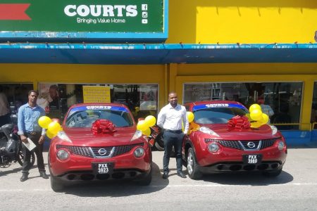 Terrence Joseph (left) and Anthony Mc Donald standing next to their brand new cars outside of the Courts Main Street branch.
