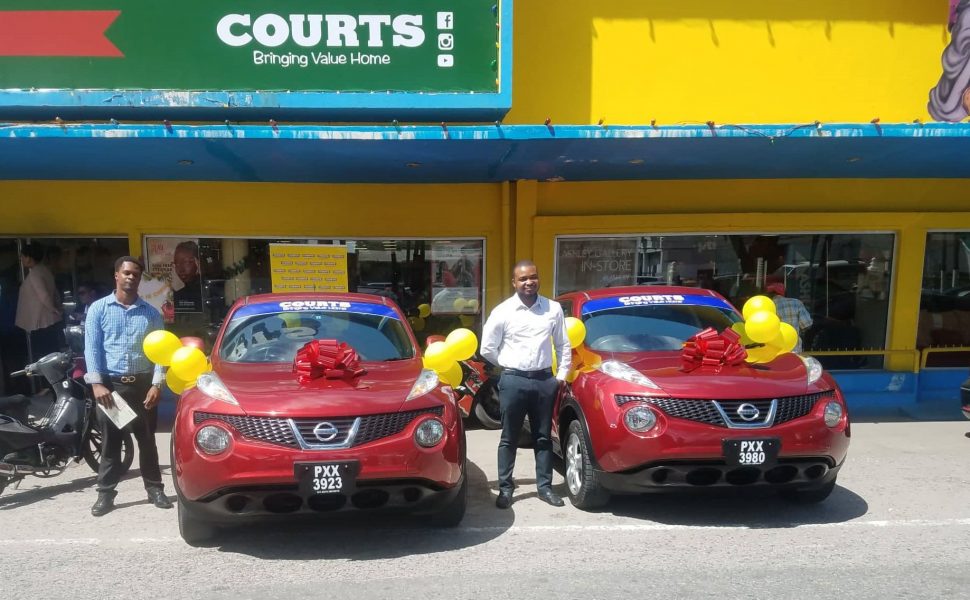 Terrence Joseph (left) and Anthony Mc Donald standing next to their brand new cars outside of the Courts Main Street branch.
