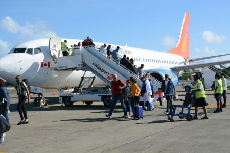 Passengers disembark from a Sunwing Airlines jet after it landed the ANR Robinson International Airport following its inaugural flight to Tobago from Canada yesterday.