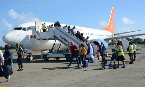 Passengers disembark from a Sunwing Airlines jet after it landed the ANR Robinson International Airport following its inaugural flight to Tobago from Canada yesterday.