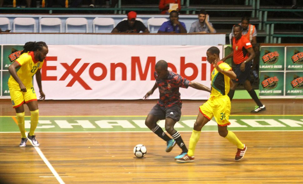 Selwyn Isaacs (centre) of East Coast Demerara Allstars trying to maintain possession of the ball while being pursued by Team Guyana’s Delroy Dean (left) and Curtez Kellman at the Cliff Anderson Sports Hall in the ExxonMobil International Futsal Festival. (Orlando Charles photo)