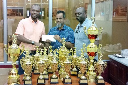 Proprietor Nazr Mohamed [center] of Mohamed’s Enterprise, donating the trophies, replicas and undisclosed to GFF Executive Member Dion Inniss. Also present is tournament coordinator Aubrey ‘Shanghai’ Major, Co-Director of the Kashif & Shanghai Organization
