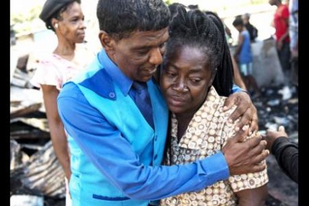 Ray Singh comforts his church sister, Jennifer Bailey, a victim of a fire which gutted a yard with 25 houses and left more than 40 residents homeless in Cockburn Gardens yesterday.