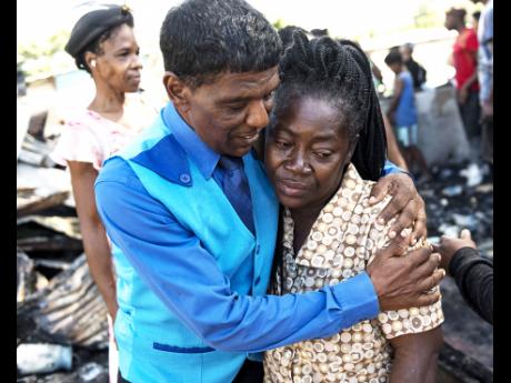 Ray Singh comforts his church sister, Jennifer Bailey, a victim of a fire which gutted a yard with 25 houses and left more than 40 residents homeless in Cockburn Gardens yesterday.