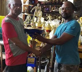 Ramesh Sunich, proprietor of the Trophy Stall, presents the first place trophy to Terrence Mitchell, President of the Upper Demerara Football Association. 