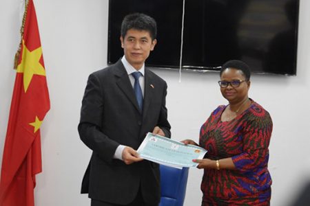 Minister of Public Health, Volda Lawrence (right) receives a certificate which verifies the receipt of items from Hu Hanming, Economic and Commercial Counsellor, Embassy, People’s Republic of China. (DPI photo)