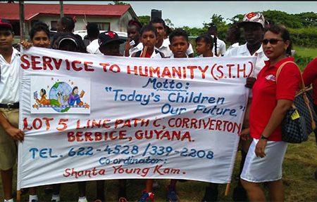 Shanta Youngkam, founder and coordinator of Service to Humanity and students display the organisation's banner.
