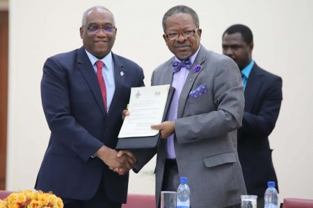 Professor Brian Copeland and Professor Ivelaw Griffith display the Memorandum of Understanding between the University of the West Indies and the University of Guyana to administer a Master’s of Science Degree in Petroleum Engineering. (Photo by Terrence Thompson)