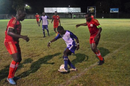 Lennox Cort [centre] of GFC trying to maintain possession of the ball while being challenged by two GPF players in the GFA ‘Revival Cup’ finale at the GFC ground, Bourda.