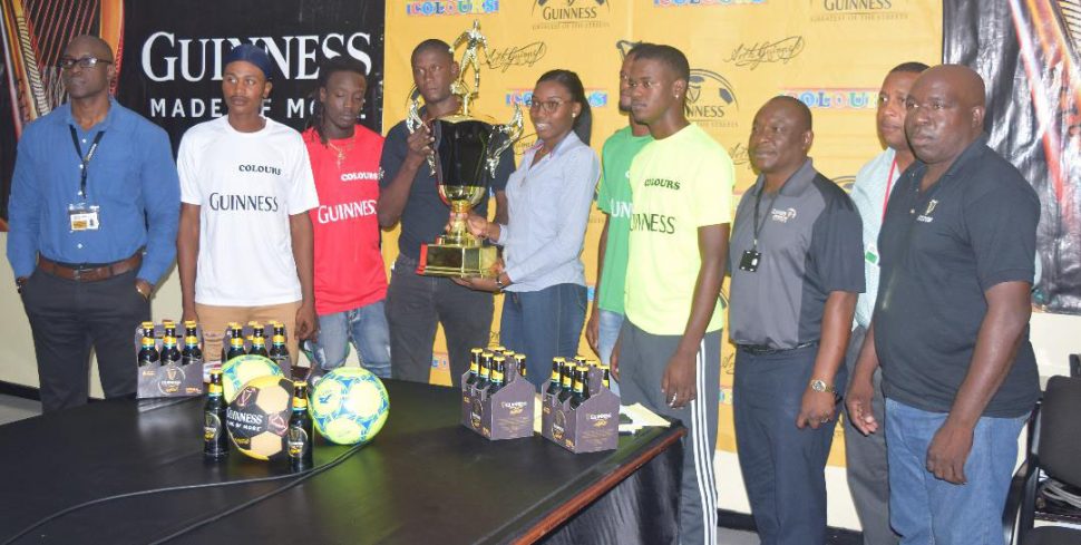 Tournament coordinator Travis ‘Zoti’ Bess, collecting the championship trophy from Colours Boutique representative Creanna Damon at the launch of the 5th West Demerara/East Bank Demerara leg of the Guinness ‘Greatest of the Streets’ Championship. Also in photo are several representatives from the competing teams as well as Guinness Brand Executive Lee Baptiste [1st from left], Banks DIH Outdoor Events Manager Mortimer Stewart [2nd from right] and Communications Director Troy Peters [3rd from right]. 