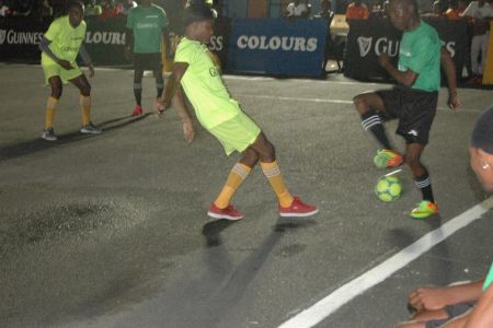 Leo Lovell [centre] of Up-Top-Bosses, in the process of challenging a Boom Bang player for the ball during the opening clash in the Guinness ‘Greatest of the Streets’ West Demerara/East Bank Demerara Zone at the Pouderoyen Tarmac
