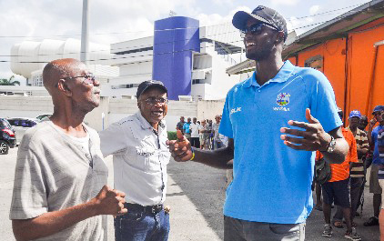 West Indies Test captain Jason Holder (right) has the attention of a couple of fans at the Kensington Oval ticket office.