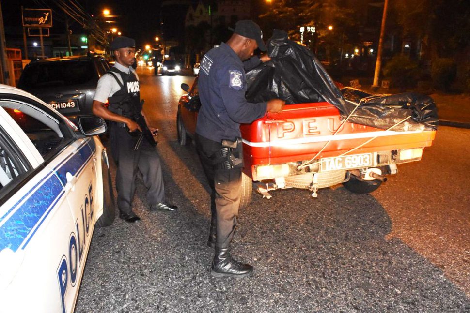 A police officer searches a vehicle during Operation Strike Back on Ariapita Avenue, Port-of-Spain on Saturday. TTPS
