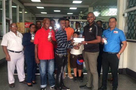 Champion Cyclist and Club Captain, Balram Narine receives a cheque from Supervisor, Fawaaz Harry watched by  Berbice Branch Manager, Reginald Matthews, Coach of FACC, Randolph Roberts, supervisor Nandram Basdeo and other club cyclists and Banks DIH Employees.
