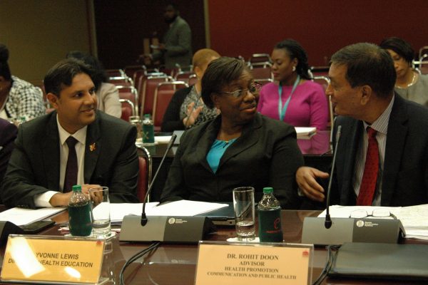 Chief Medical Officer of Health Dr Roshan Parasram, left, speaks with Health Education director Yvonne Lewis, and Health Promotion, Communication, and Public Health adviser Dr Rohit Doon at a Joint Select Committee inquiry in Parliament.