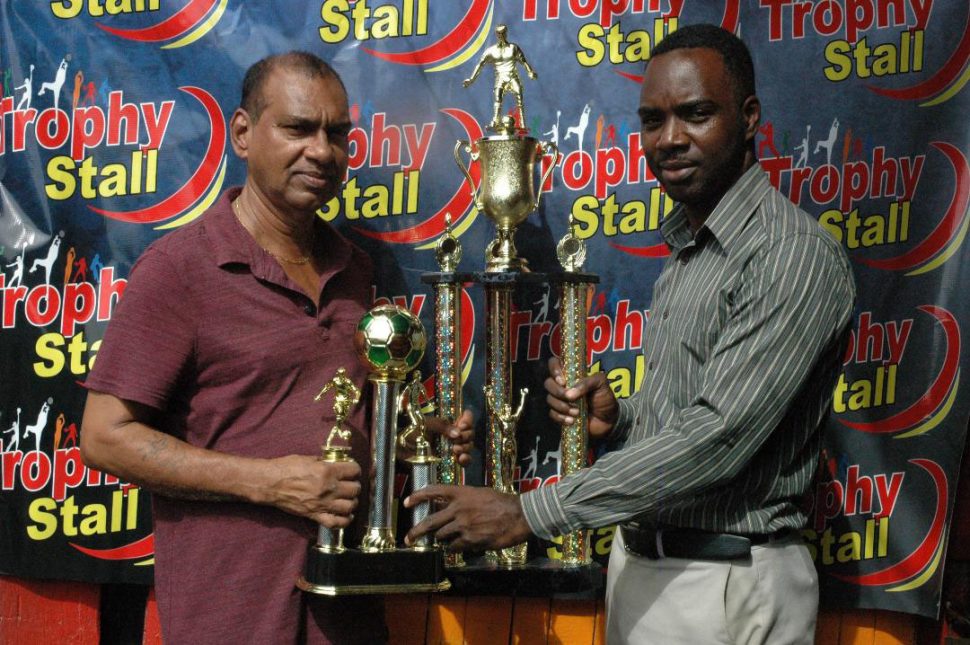 Managing Director of Trophy Stall Ramesh Sunich hands over the second and third place trophies to tournament coordinator Esan Griffith
