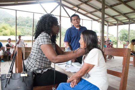 Waipa’s Toshao looks on as Dr. Kay Shako (left) examines one of the residents who accessed services at the medical outreach. (DPI photo) 