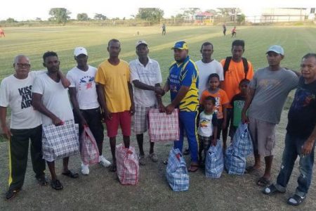 Shan Satar (in the Young Warriors Cricket Club uniform) hands over the hampers to the recipients.