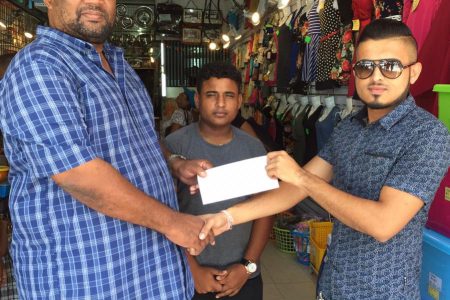 Ryan Singh (right) hands over the sponsorship cheque to BCB President Hilbert Foster in the presence of BCB PRO Simon Naidu.