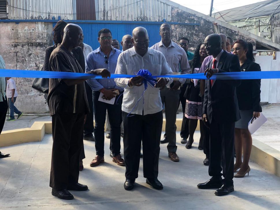 Minister of Finance Winston Jordan (at centre) cutting the ribbon to officially commission the warehouse along with Managing Director Andrew Astwood (right)  