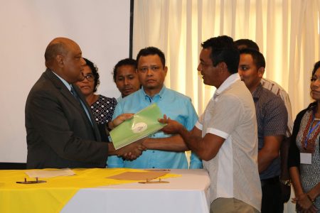 Minister of Natural Resources, Raphael Trotman (left), handing over a signed copy of the MoU to the Chairman on the National Toshaos Council, Nicholas Fredericks. 
