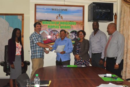 Minister of Indigenous Peoples’ Affairs Sydney Allicock (at centre) and Director of the Guyana Tourism Authority (GTA) Brian Mullis (second, from left) exchanging signed copies of the Memorandum of Understanding, while flanked by Junior Minister Valerie Garrido-Lowe (third, from right) Permanent Secretary Alfred King ( second, from right) and other staff members of the ministry.