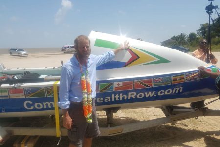 Richard Allen posing next to the boat that he rowed in from Sierra Leone to Guyana