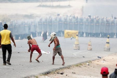 People throw stones at Venezuela’s National Guard members, at the border, seen from in Pacaraima, Brazil yesterday. REUTERS/Ricardo Morales 