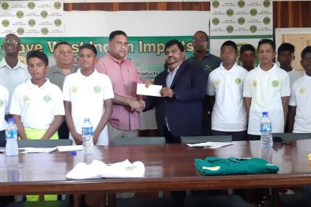 Dave Narine (right) hands over the sponsorship cheque of the 2019 GCB/Dave West Indian Imports Inter-County Under-15 tournament to Guyana Cricket Board’s Anand Kalladeen in the presence of some of the players and officials
