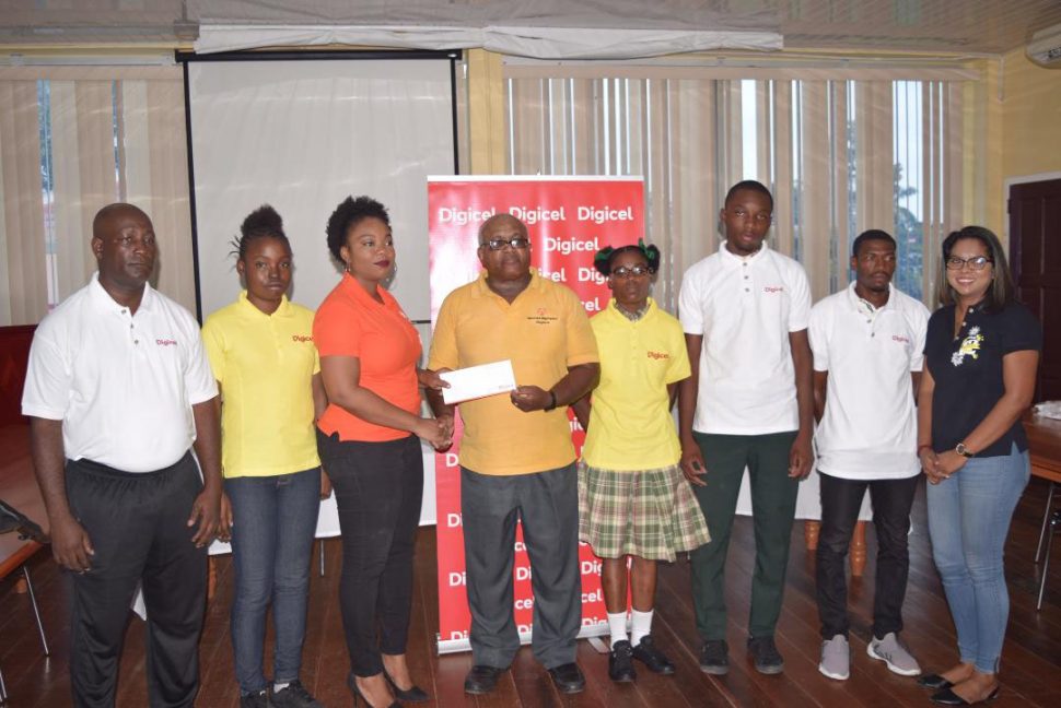 Wilton Spencer, Head of the Special Olympics Committee receives the sponsorship pact from Louanna Abrams, Sponsorship Manager at Digicel in the presence of the athletes, coach and Digicel’s Communication Manager, Vidya Sanichara.