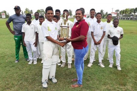 Demerara Cricket Board’s Kavita Yadram presents the 2019 Demerara Cricket Board U15 Inter-Association trophy to Georgetown skipper, Alvin Mohabir in the presence of the other members of the team.