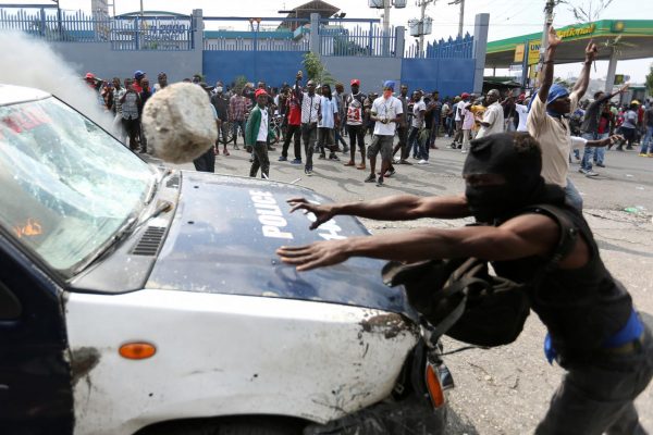 A demonstrator throws a rock at a police car during a protest against former government officials accused of misusing Petrocaribe funds and the country's inflation rate in Port-au-Prince, Haiti February 7, 2019. REUTERS/Jeanty Junior Augustin