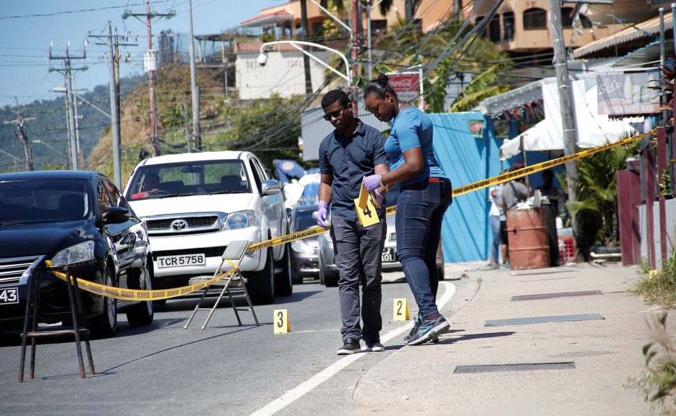 Crime Scene Investigators search for spent rounds following the early morning shooting of three women along the Carenage Main Road on Saturday.