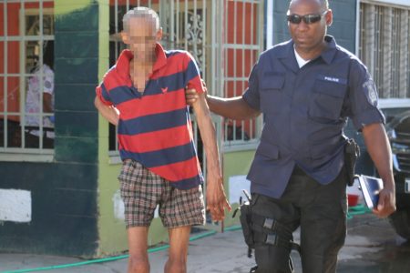 A police officer escorts one of the rescued residents from the senior citizens home in Arima yesterday.