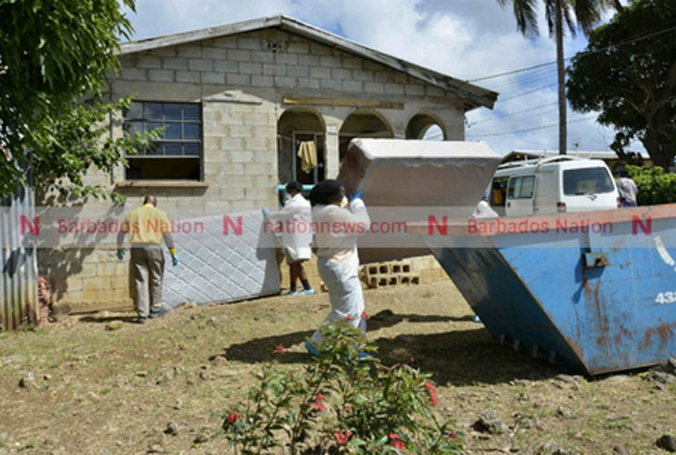 Personnel from a cleaning agency disposing of a bloody bed base yesterday afternoon.(Pictures by Lennox Devonish.)