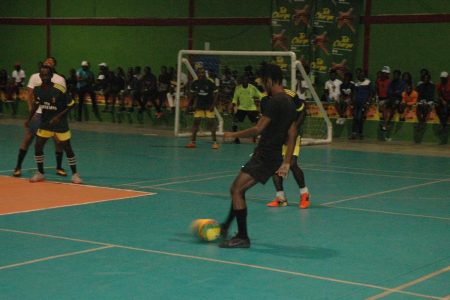 Sunil Logan [black] of Hustlers attempting a pass moments before his equalising goal against Alexander Village on the third night of the Magnum Mash Futsal Championship at the National Gymnasium, Mandela Avenue.
