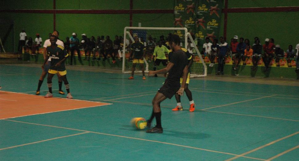 Sunil Logan [black] of Hustlers attempting a pass moments before his equalising goal against Alexander Village on the third night of the Magnum Mash Futsal Championship at the National Gymnasium, Mandela Avenue.
