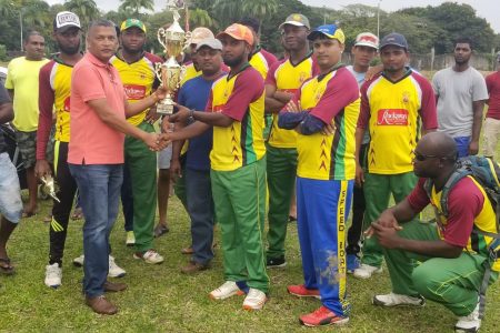 President of the West Demerara Cricket Association Anand Sanasie hands over the winning trophy to Independence A.
