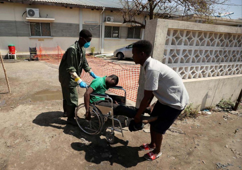 A medical staff member wears a protective mask as he assists a man arriving at a cholera treatment centre set up in the aftermath of Cyclone Idai in Biera, Mozambique. (REUTERS/Mike Hutchings) 
