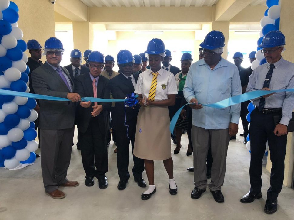 A Queen’s College student cutting the ribbon to officially open the warehouse yesterday morning as Executive Chairman Komal Samaroo (left), Yesu Persaud (second, from left), Minister of Foreign Affairs Carl Greenidge (third, from left), Minister of Finance Winston Jordan (second, from right) and Minister of Business Dominic Gaskin (right) look on. 