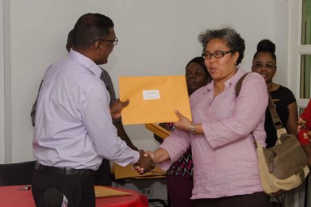Executive Director of the Guyana Responsible Parenthood Association (GRPA) Renata Chuck-A-Sang collects the certificate of compliance from Chief Medical Officer Shamdeo Persaud. (Department of Public Information photo) 