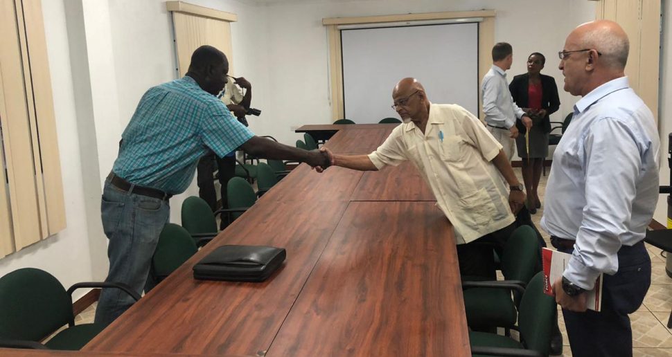 General Secretary of the Guyana Bauxite and General Workers Union Lincoln Lewis (at left) greeting labour advisor to the Bauxite Company of Guyana Inc. (BCGI) Mohamed Akeel yesterday morning in the presence of representative of the company Vladimir Permyakov (right).