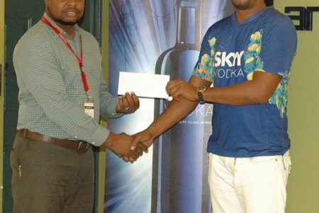 Richard Mittleholzer [right] collecting the sponsorship cheque from Skyy Vodka brand representative Edison Jefford at Ansa McAl’s headquarters yesterday.