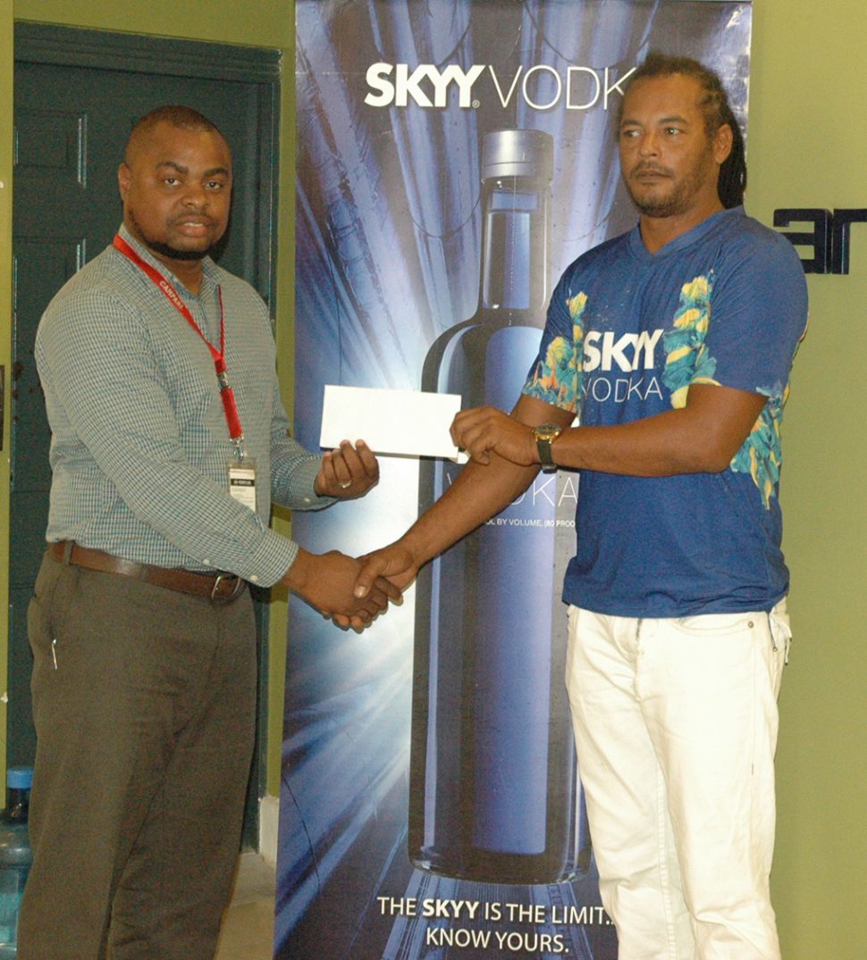 Richard Mittleholzer [right] collecting the sponsorship cheque from Skyy Vodka brand representative Edison Jefford at Ansa McAl’s headquarters yesterday.