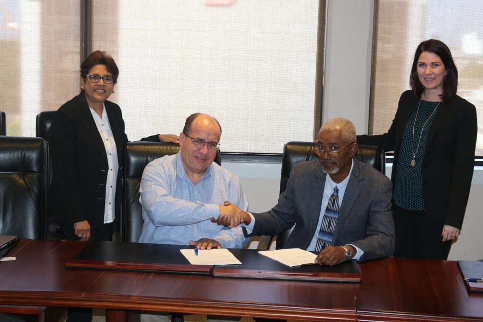 David Affonso (second from left), Chairman, Massy Distribution and Brian Ramsey, Regional Development Director, Amalgamated Security shake hands after having signed the share purchase agreement for Massy Security (Guyana) Inc. Looking on are  Chandrakali Maharaj (left), Senior Legal Counsel Massy Limited and Melissa Inglefield, Partner M. Hamel-Smith & Company.
