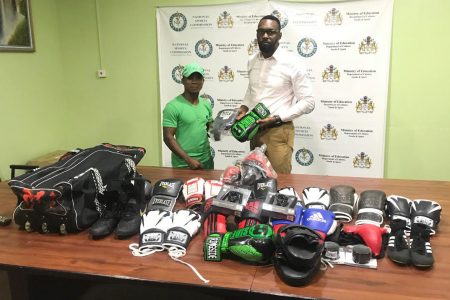 Coach at the Pocket Rocket Gym in Linden, Orlan ‘Pocket Rocket’ Rogers receiving a quantity of boxing gear from Director of Sports Christopher Jones. 